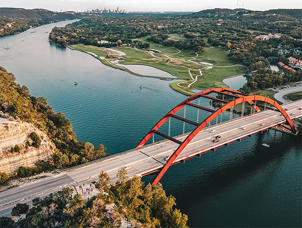 Vista aérea de um rio e uma ponte em Austin, Texas, com a cidade em segundo plano.