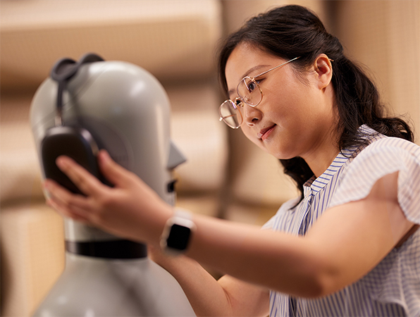 Una persona del equipo de Hardware de Apple acomodando unos AirPods Max de Apple en un maniquí de laboratorio.