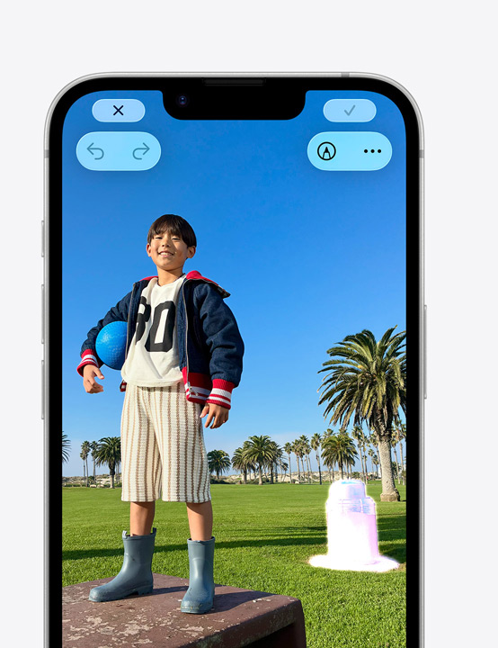 iPhone Display, Foto einer lächelnden Person auf einer Parkbank, mit dem Bereinigen Tool wird eine Mülltonne im Hintergrund entfernt
