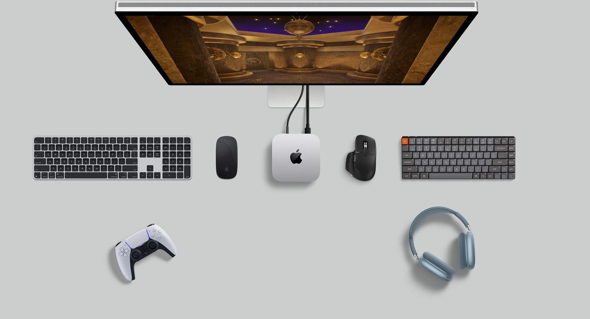 俯視圖展示銀色 Mac mini 擺放在桌上,旁邊放有一部顯示器、無線鍵盤、無線滑鼠、一個遊戲手掣,以及 AirPods Max。