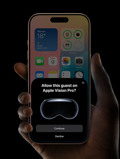 一隻手拿著一部 iPhone。iPhone 的螢幕上有一個視窗，顯示「要在 Apple Vision Pro 上允許此訪客嗎？」的訊息 ，底下有「繼續」和「拒絕」兩個按鈕。