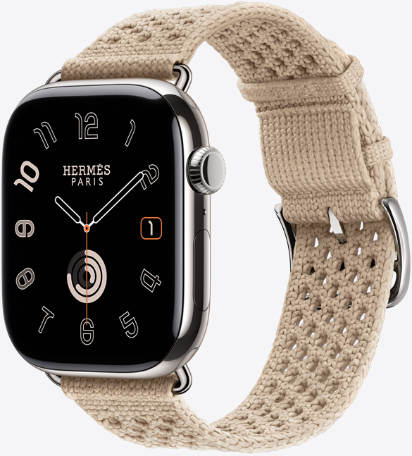 Apple Watch Hermès Series 11, titanium case, silver colour, polished finish, edge-to-edge display, rounded corners, right side exterior, Digital Crown, microphone, side button, Circulaire watch face (hour, minute, second hands, Hermès Paris logo), paired with Néo Tricot strap, argile colour (beige), knit polyamide yarn material, adjustment holes centred, silver colour buckle and hardware