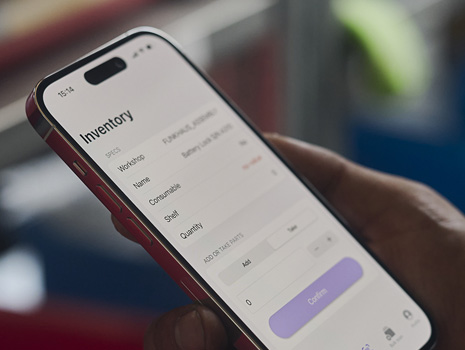 Gros plan d’une main tenant un iPhone sur lequel est affiché une app de suivi des stocks.