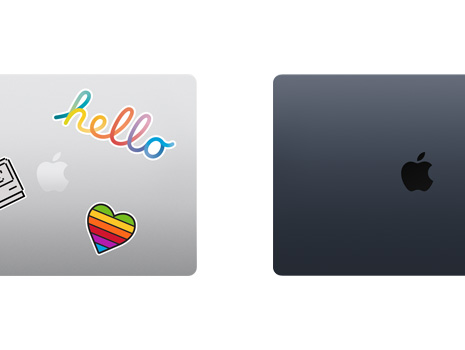 Vue en plongée de deux portables Mac fermés, dont un est décoré d’autocollants.