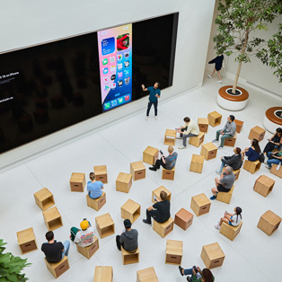 MacBook을 갖고 있는 Apple Store 직원이 다른 사람과 상호작용하는 모습.