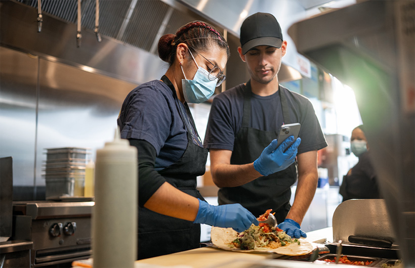 Een werknemer leert hoe je een burrito op de ‘Sisig-manier’ oprolt.