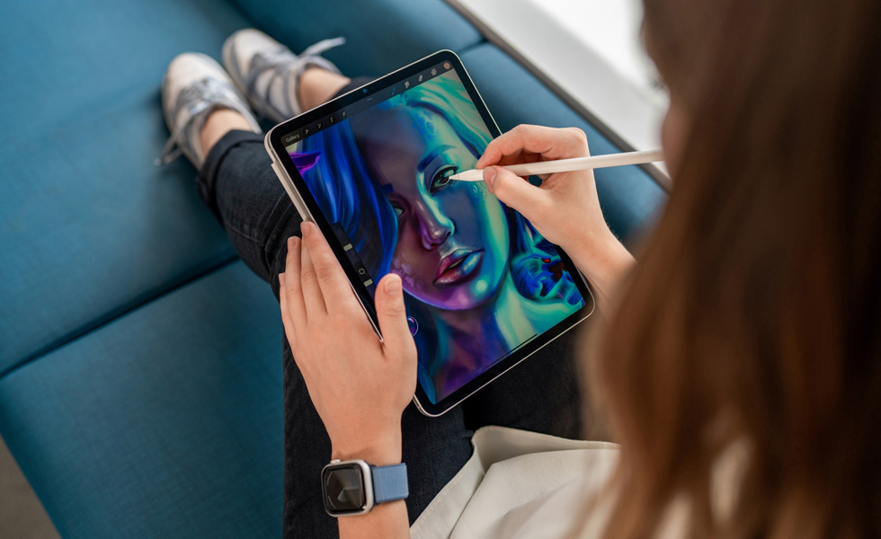 Estudiante usando un Apple Pencil y la app Procreate para dibujar en el iPad que tiene en el regazo
