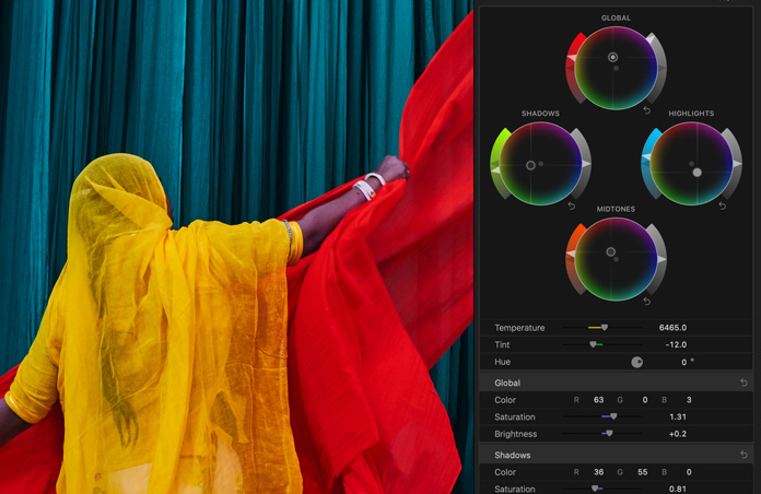 Screen showing woman in brightly coloured yellow sari with red scarves against blue background, demo of colour grading tools