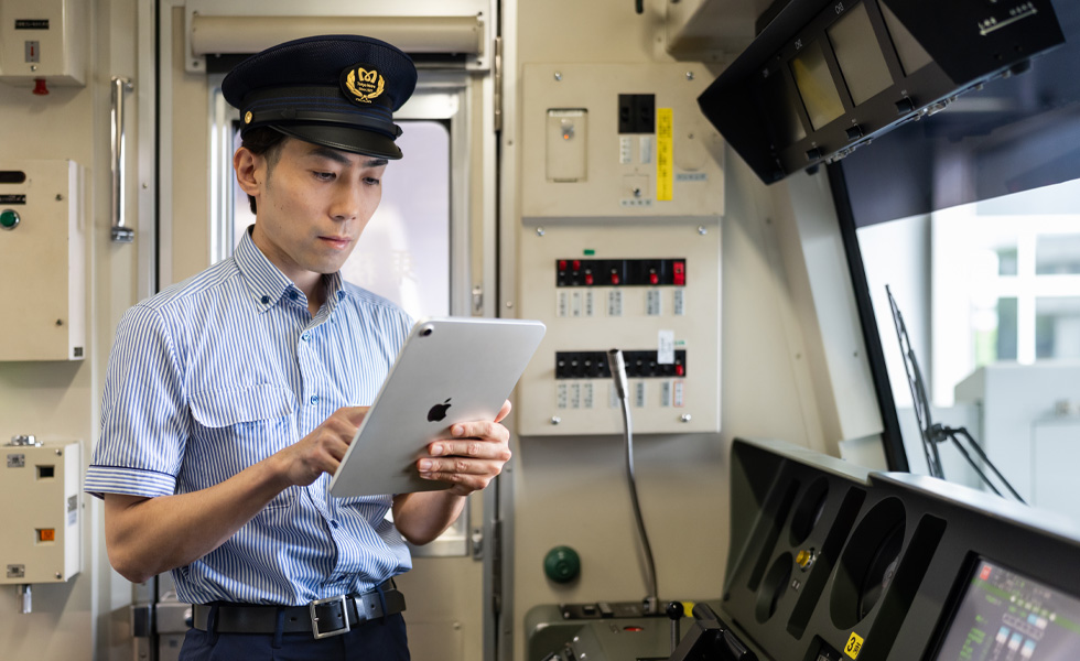 Un conducteur utilise un iPad debout dans la cabine éclairée de son train.