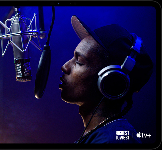 iPad Pro, landscape orientation, front exterior, space black colour, rounded corners, black display bezel, display showing AppleTV+ playing a scene from the Apple TV+ original film Highest 2 Lowest with ASAP Rocky as Yung Felon rapping into a microphone