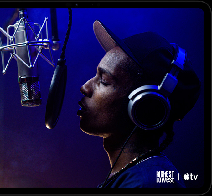 iPad Pro, landscape orientation, front exterior, space black colour, rounded corners, black display bezel, display showing AppleTV+ playing a scene from the Apple TV+ original film Highest 2 Lowest with ASAP Rocky as Yung Felon rapping into a microphone