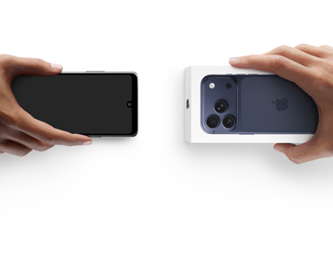 Hands exchanging phones, Android on the left without a box, on the right is a new iPhone 17 Pro in the box.