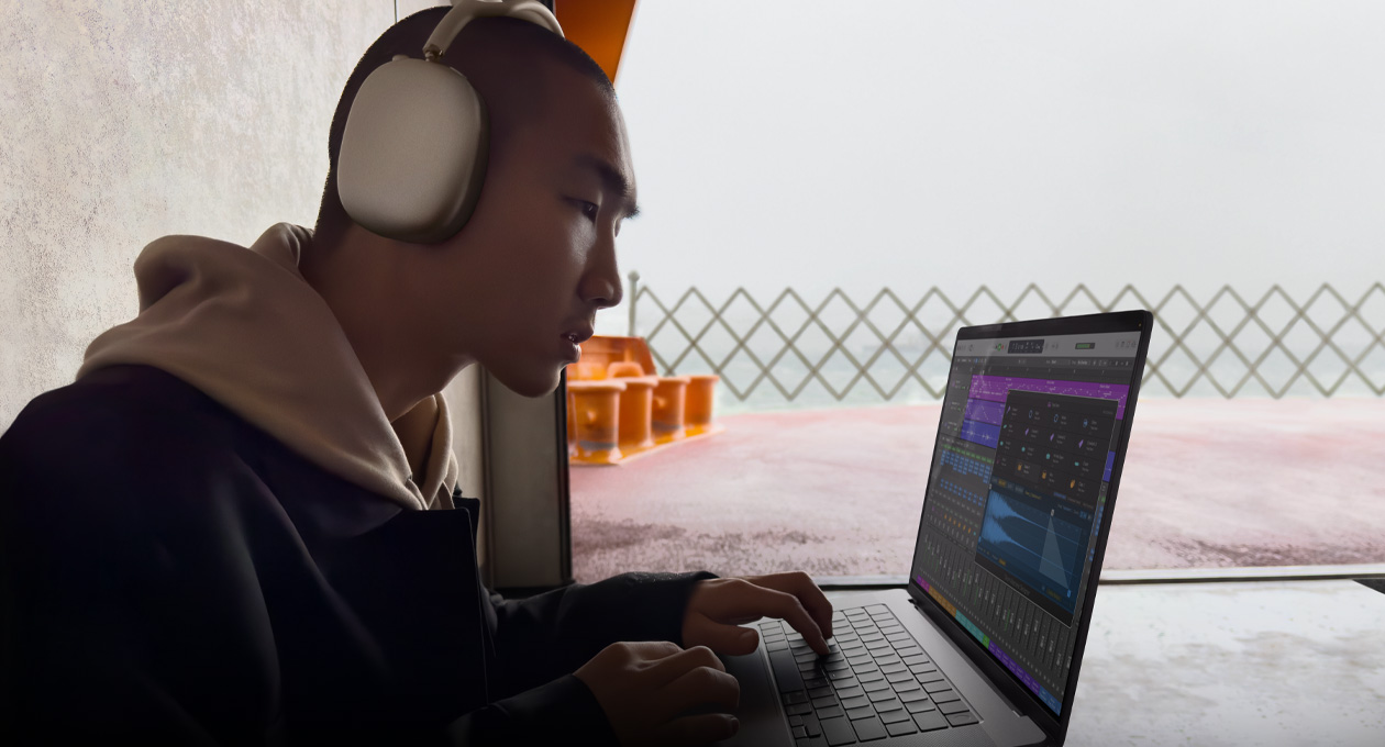 Une personne de profil, portant des AirPods Max et utilisant Logic Pro sur un MacBook Pro 16 pouces