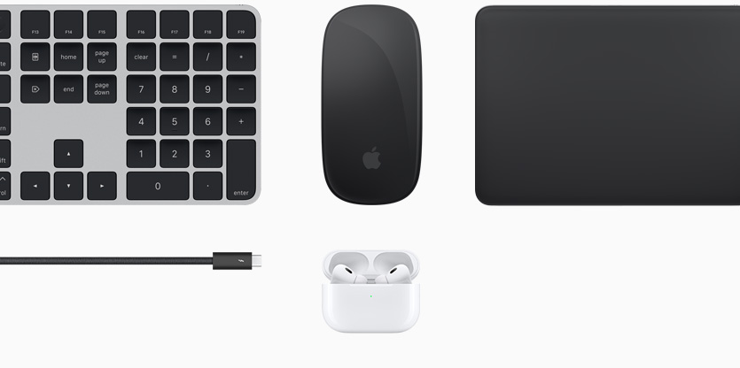 Vários acessórios para Mac, incluindo um Magic Keyboard com Touch ID preto, Magic Mouse preto, Magic Trackpad preto, cabo para acessórios preto e AirPods em branco dentro da caixa de carregamento branca aberta