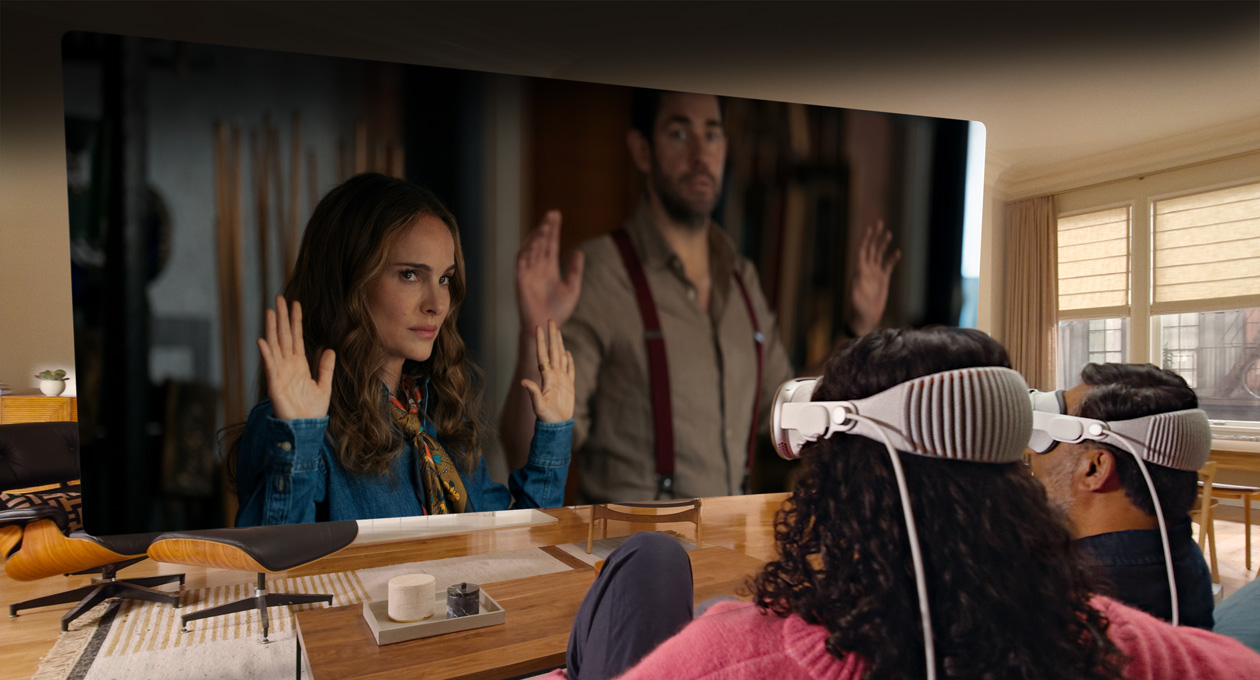 Two people both wearing Apple Vision Pro sit side by side on a couch watching: Fountain of Youth movie, displayed on a screen stretching across the room