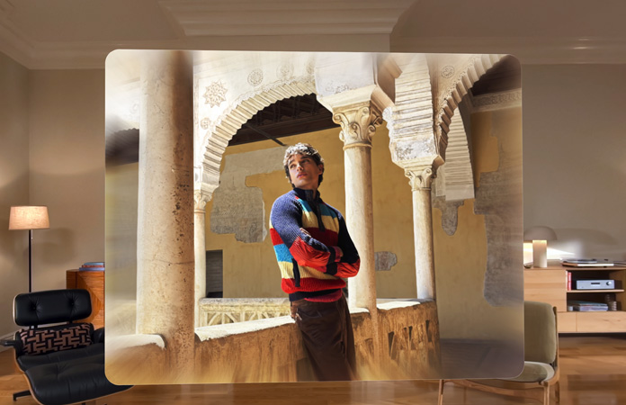 Spatial scene in photo of man leaning against balcony of winding courtyard, with depth and dimension in surroundings