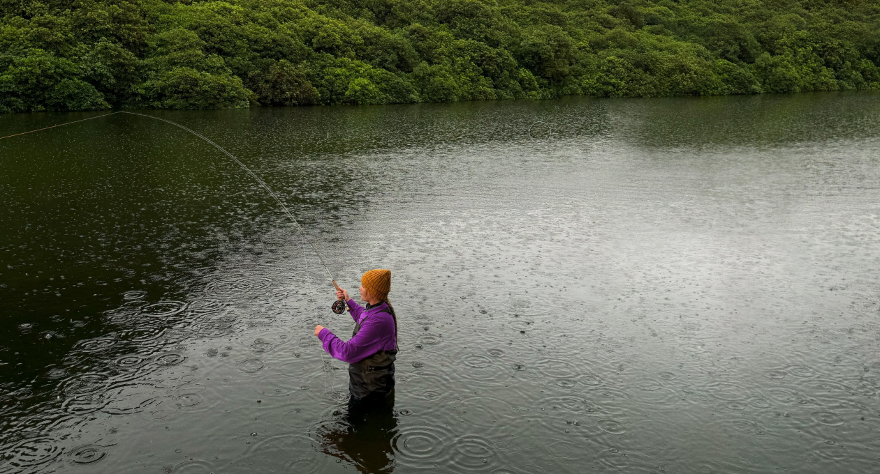 Photo d’une femme qui pêche à la mouche dans un lac, outil Pixelmator Pro qui supprime un objet non désiré en arrière-plan qui est mis en surbrillance en jaune