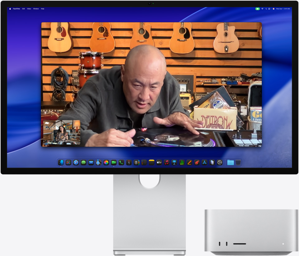 Pendant un appel vidéo sur un Studio Display XDR sous lequel est glissé un Mac Studio, une personne dans un magasin de musique regarde attentivement une table tournante