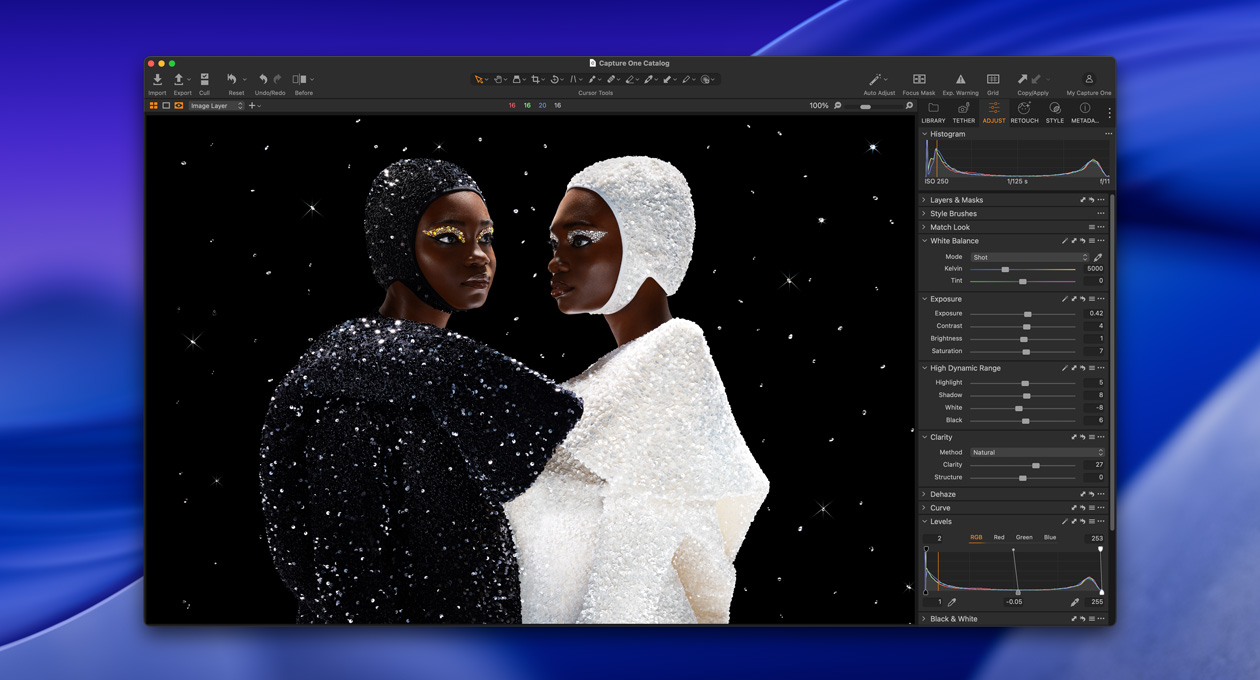 Une personne vêtue de noir se tient de biais à côté d’une personne vêtue de blanc, illustrant la luminosité et le contraste du Studio Display XDR