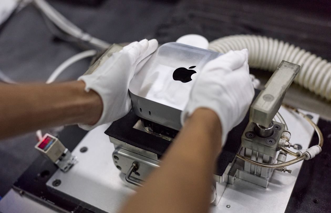 組み立て作業中にMac miniを製造機に入れている手袋を着けた手