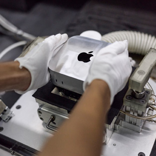 組み立て作業中にMac miniを製造機に入れている手袋を着けた手