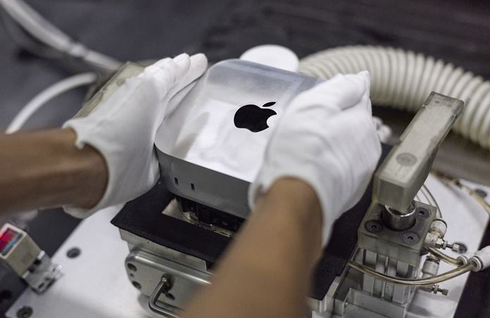 組み立て作業中にMac miniを製造機に入れている手袋を着けた手