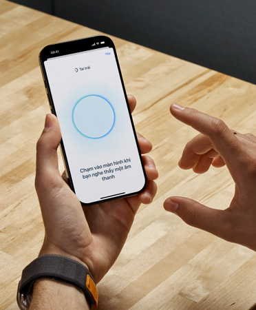 Người dùng AirPods Pro 2 cầm iPhone trong khi sử dụng tính năng Kiểm Tra Thính Giác mới