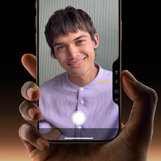 Bàn tay cầm một chiếc iPhone 16 Pro màu Titan Sa Mạc, với ngón tay cái trượt dọc theo nút Điều Khiển Camera để điều chỉnh độ sâu trường ảnh